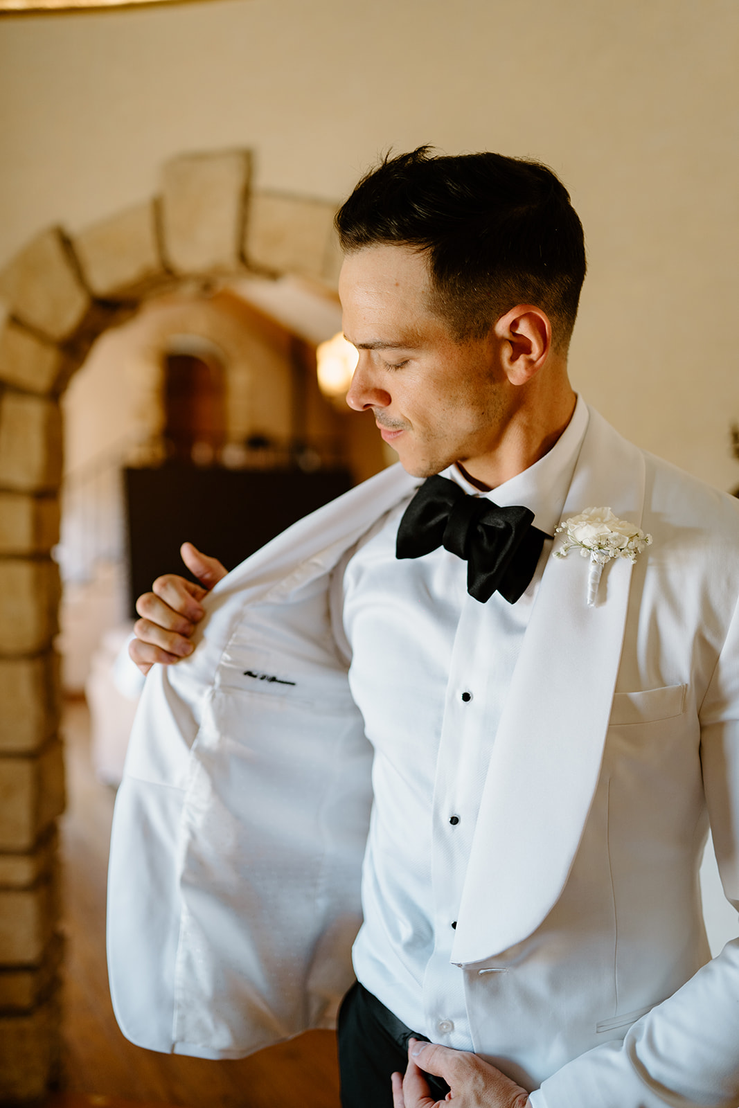 Groom looks at stitching of jacket at Chateau Noland wedding in San Luis Obispo California - Cobblestone
