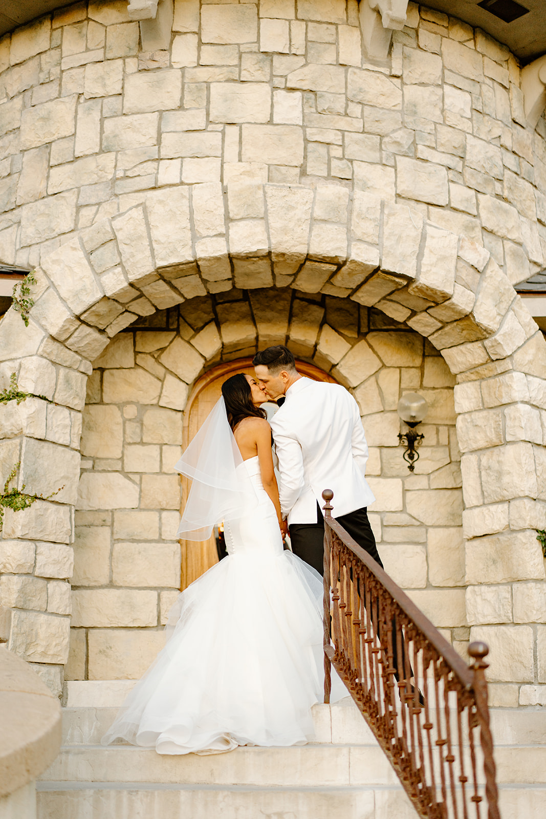 Newlyweds kiss on steps of Chateau Noland in San Luis Obispo California - Cobblestone