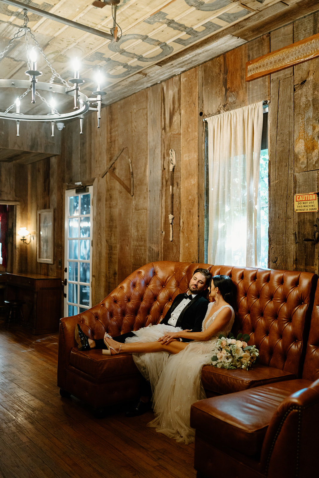 bride and groom cuddle on couch at 1880 Union Hotel in Los Alamos, Ca photography by Cobblestone
