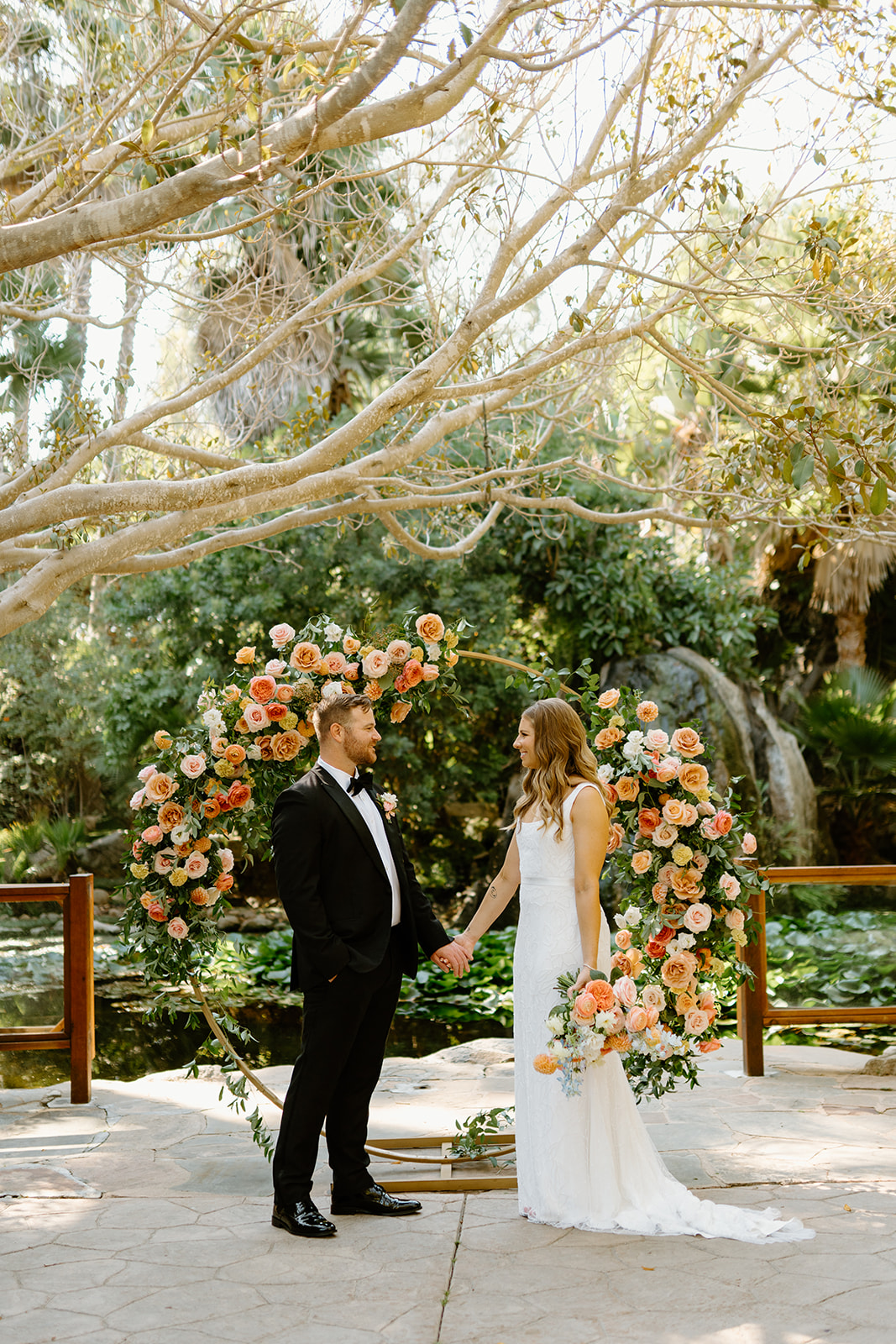 bride and groom at wedding arch Oceanside California, photography by Cobblestone Weddings