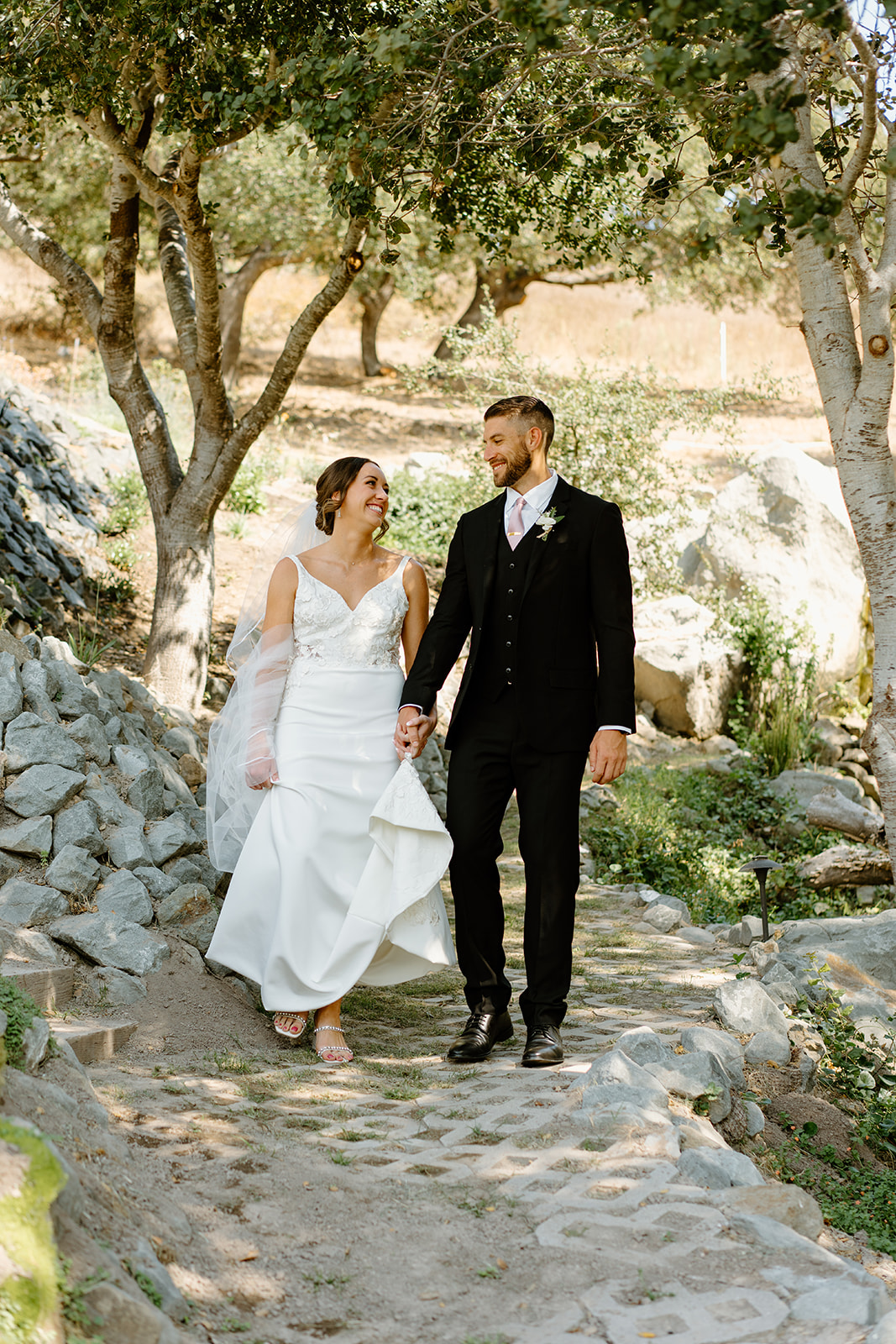 bride and groom walk down cobblestone path at wedding in San Luis Obispo CA, photography by Cobblestone