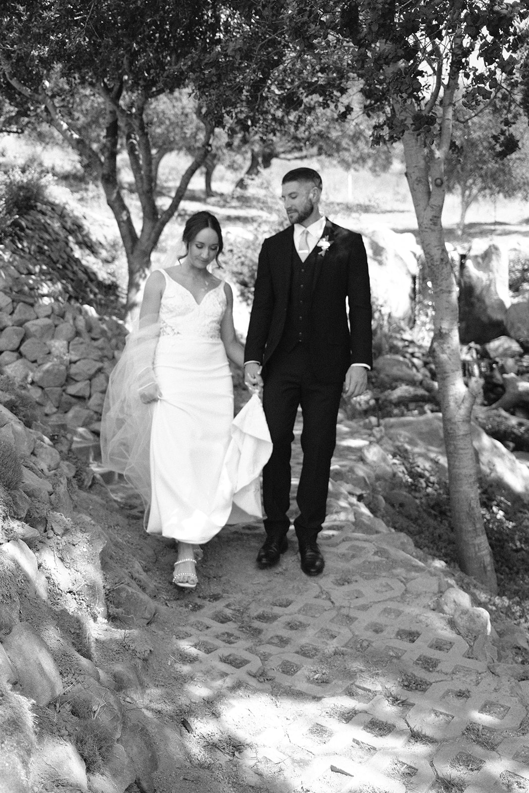 bride and groom walk down cobblestone path at wedding in San Luis Obispo CA, photography by Cobblestone