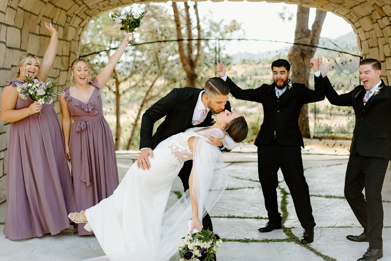 bridal party with bride and groom dip kiss at wedding in San Luis Obispo CA, photography by Cobblestone