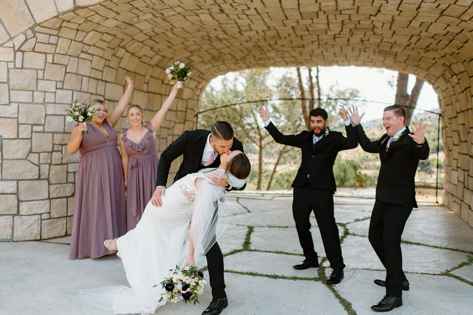 bridal party with bride and groom dip kiss at wedding in San Luis Obispo CA, photography by Cobblestone